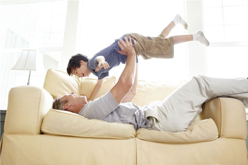 older man playing with grandson on couch