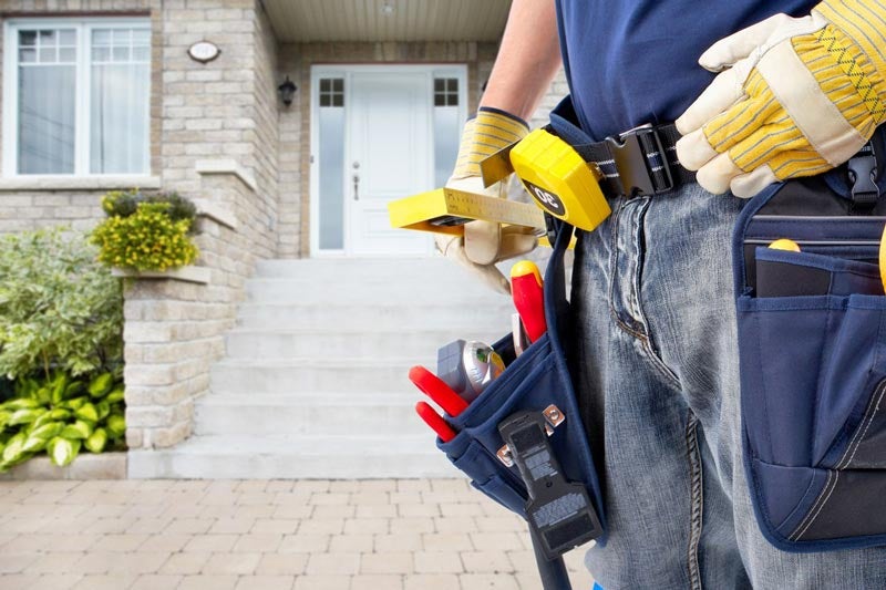 tool belt of a plumber standing outside home